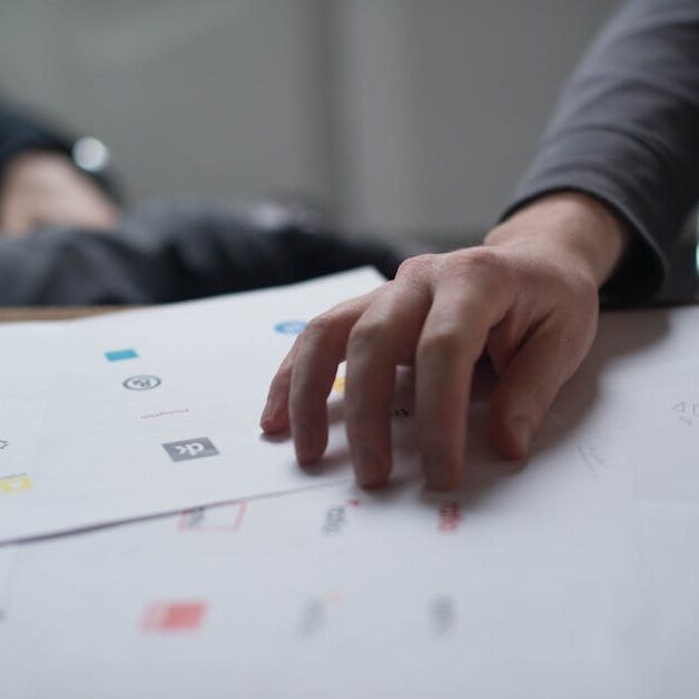 A close-up shot of a hand reviewing various logo designs on paper, ideal for business concepts.